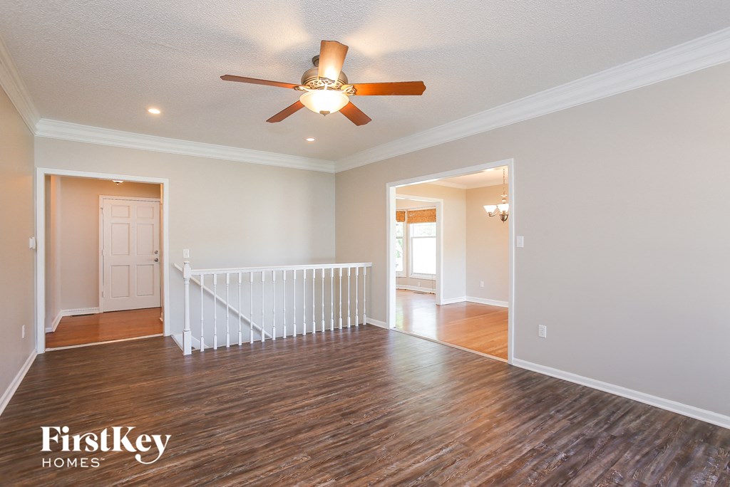 A spacious room with a wood floor and a ceiling fan.