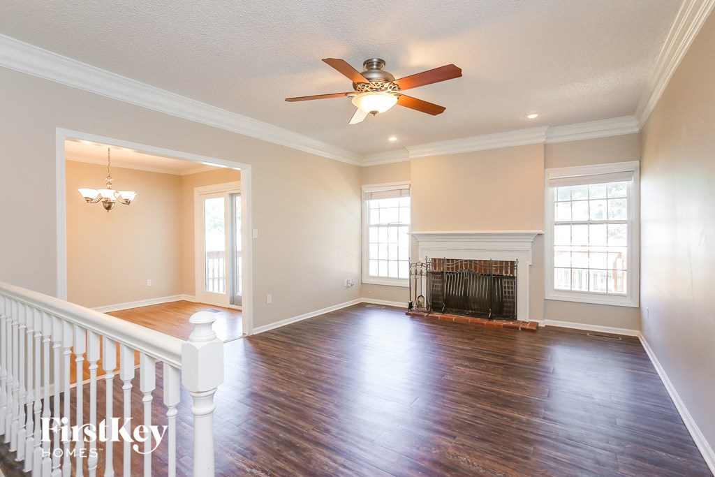 A spacious room with a fireplace and a ceiling fan.