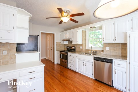 A kitchen with white cabinets and a wooden floor.