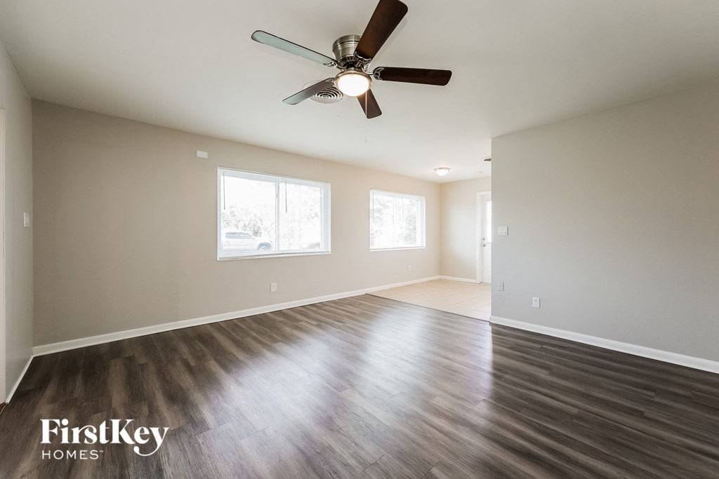A spacious room with a ceiling fan and wooden flooring.