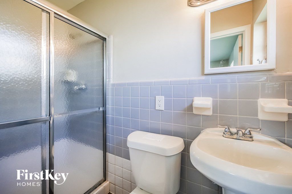 A bathroom with a white toilet, a white sink, and a mirror.