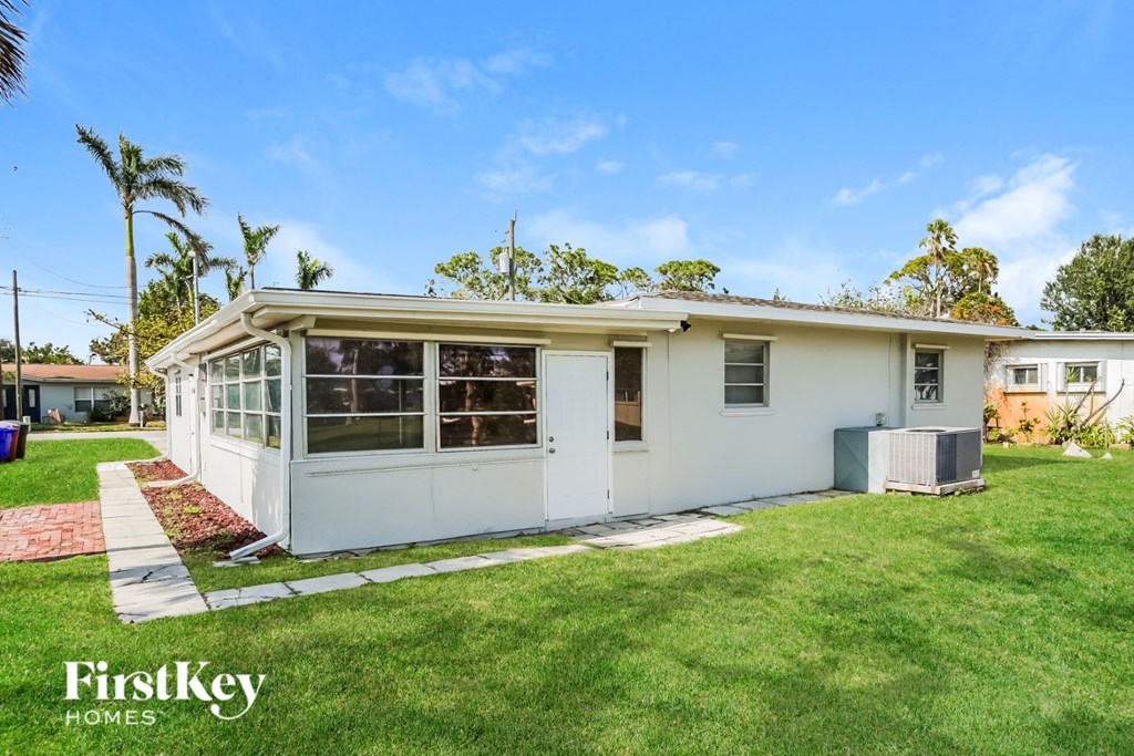 A white house with a red brick pathway in front of it.