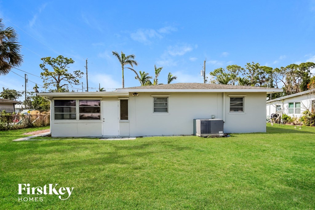 A white house with a brown roof and a green lawn in front.