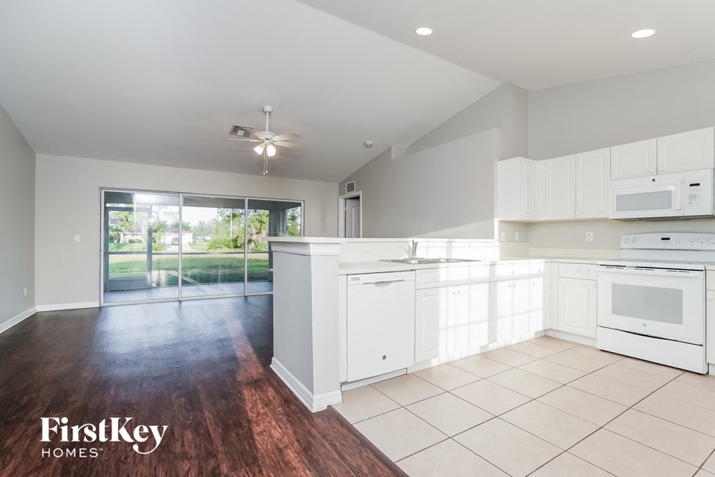 a large kitchen with white cabinets and white appliances and a sliding glass door
