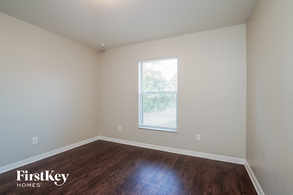 a living room with wood floors and white walls and a window
