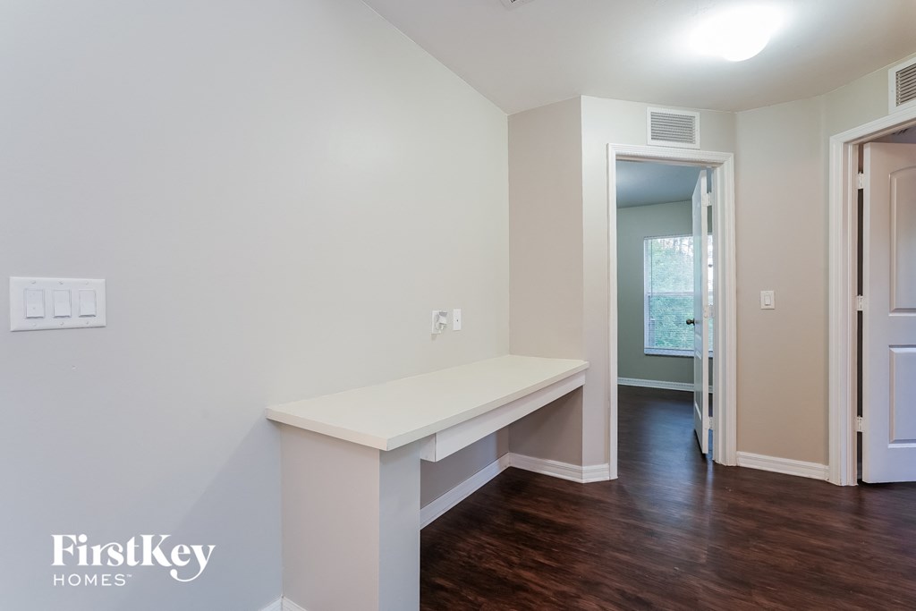 a living room with a white bench and a hallway with a door to a bathroom