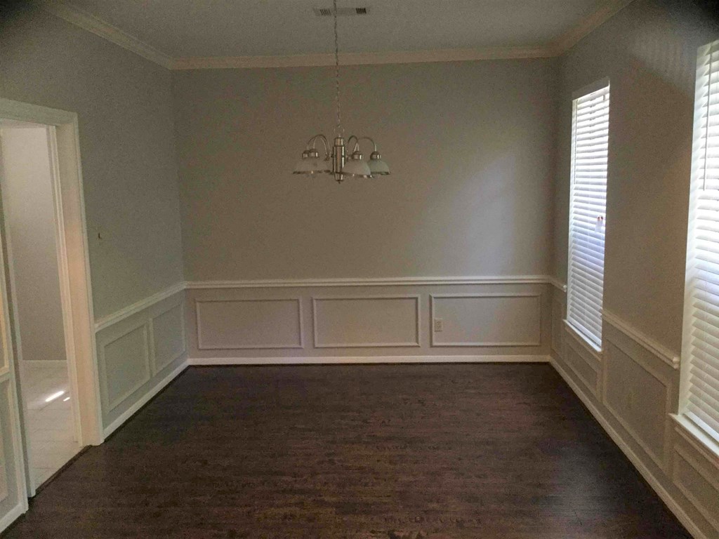 A room with a chandelier and wood flooring.