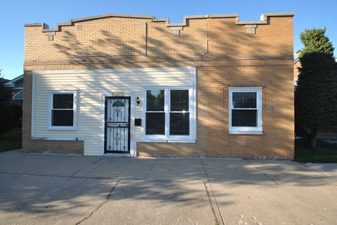 the front of a small brick building with a black door