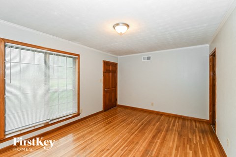 an empty living room with a large window and wood floors