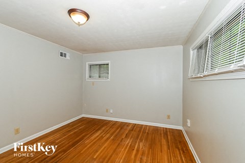 a bedroom with a hardwood floor and a window