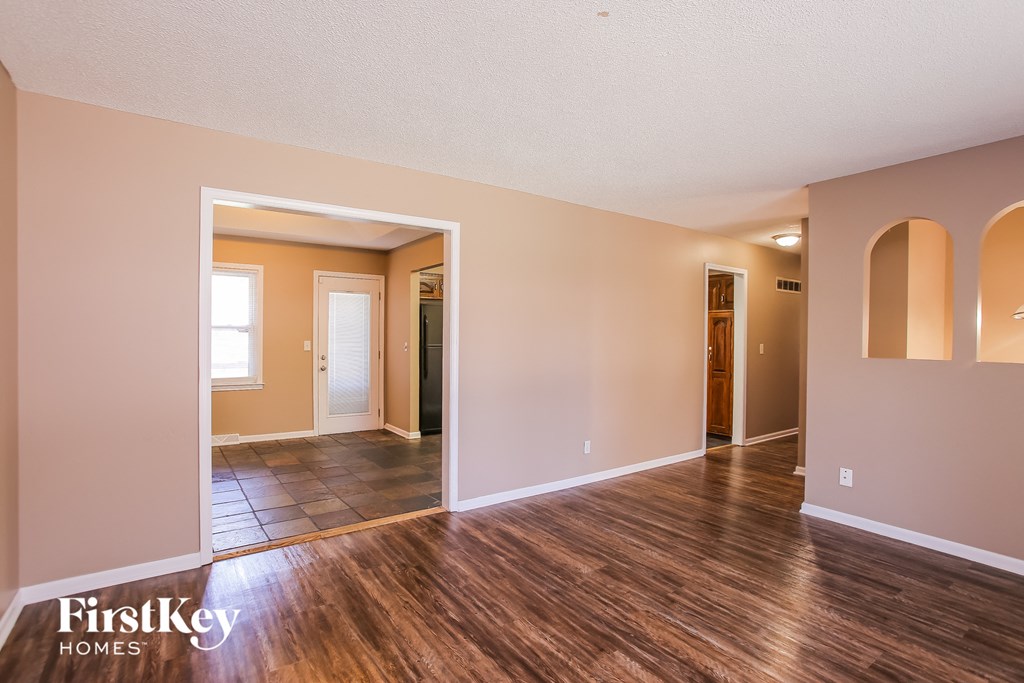 the living room and dining room of an empty house with wood flooring