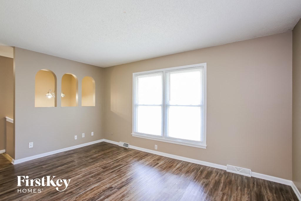 the spacious living room with hardwood flooring and a large window