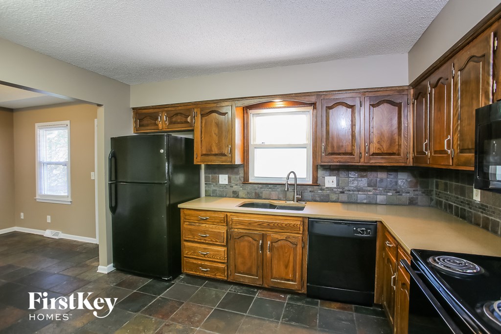 a kitchen with wooden cabinets and a black refrigerator