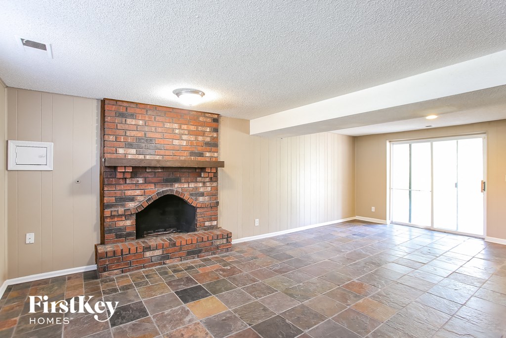 the living room has a brick fireplace and tile flooring