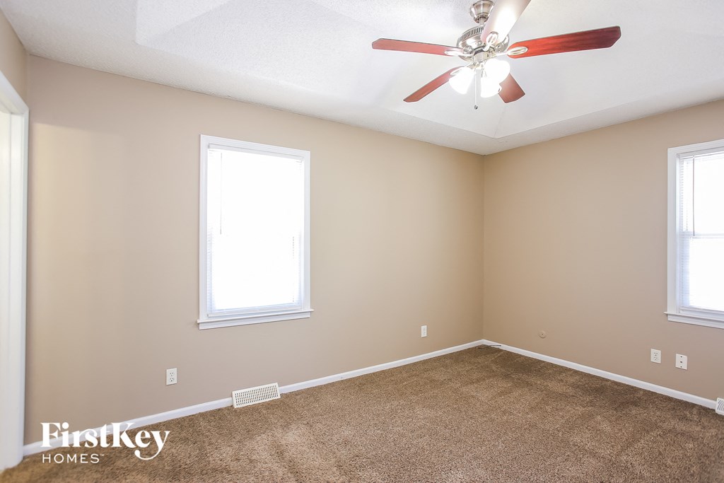 a living room with carpet and a ceiling fan