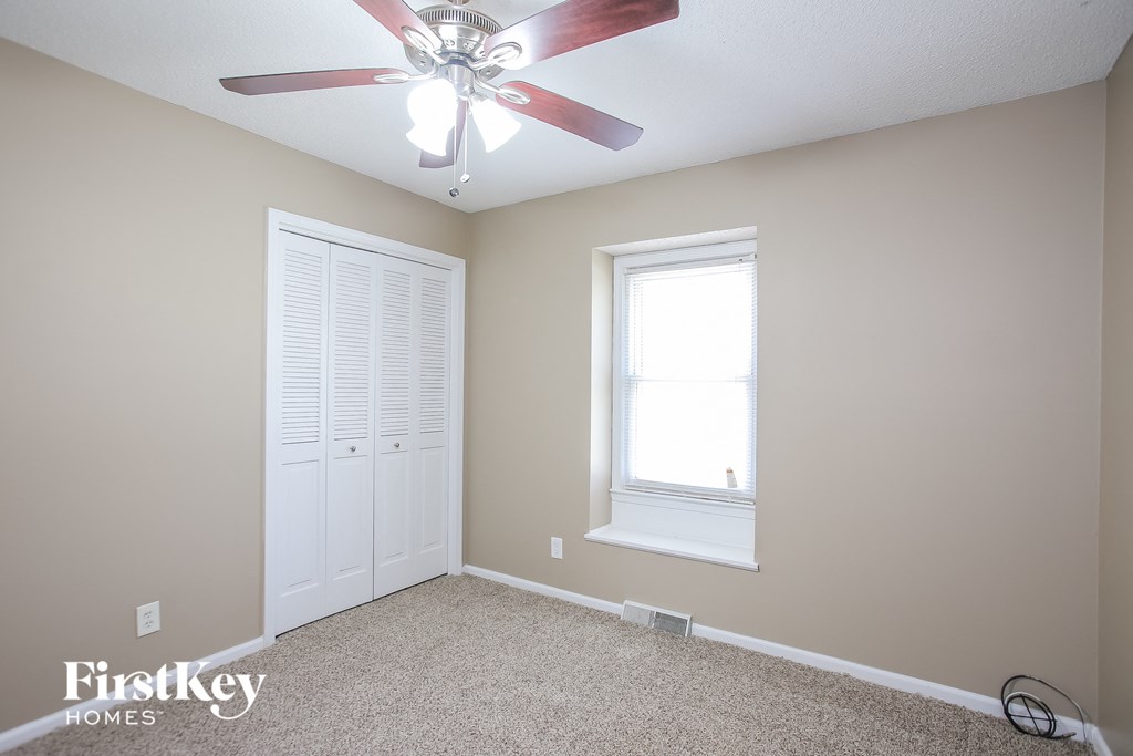 a bedroom with a ceiling fan and a closet