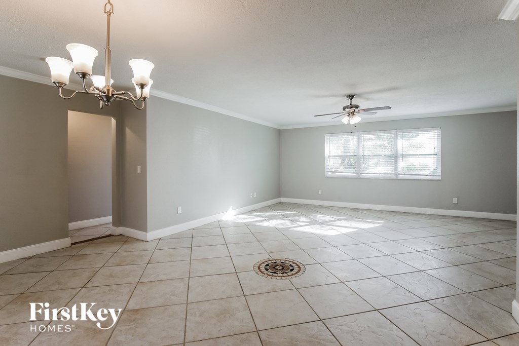 an empty living room with a ceiling fan and tiled floor