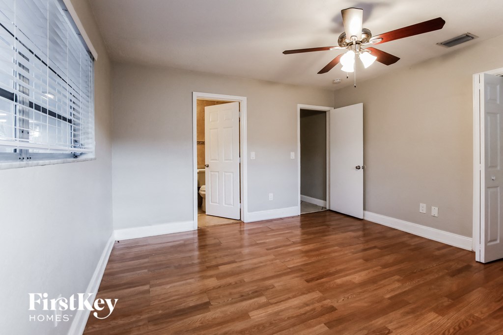 an empty living room with wood floors and a ceiling fan