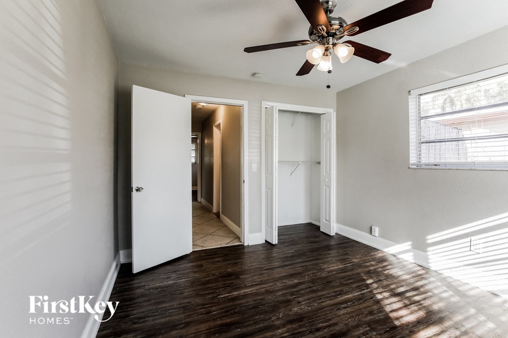 an empty living room with a ceiling fan and a door to a hallway