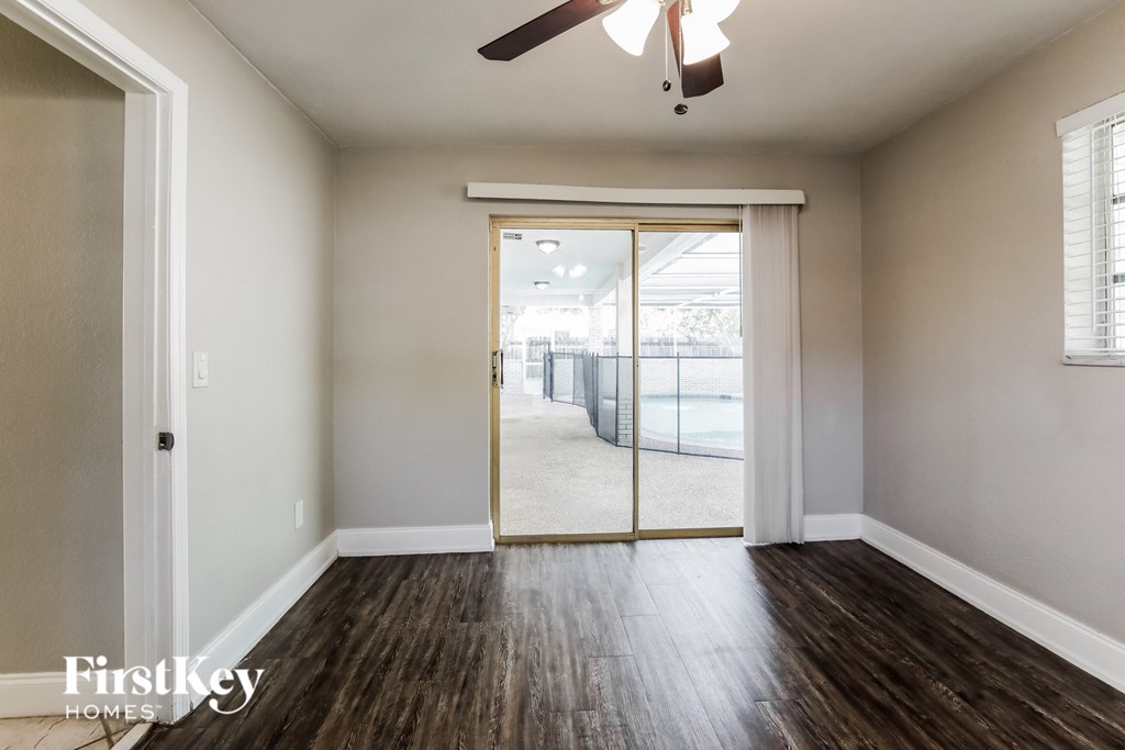 an empty living room with a ceiling fan and sliding glass doors to a balcony