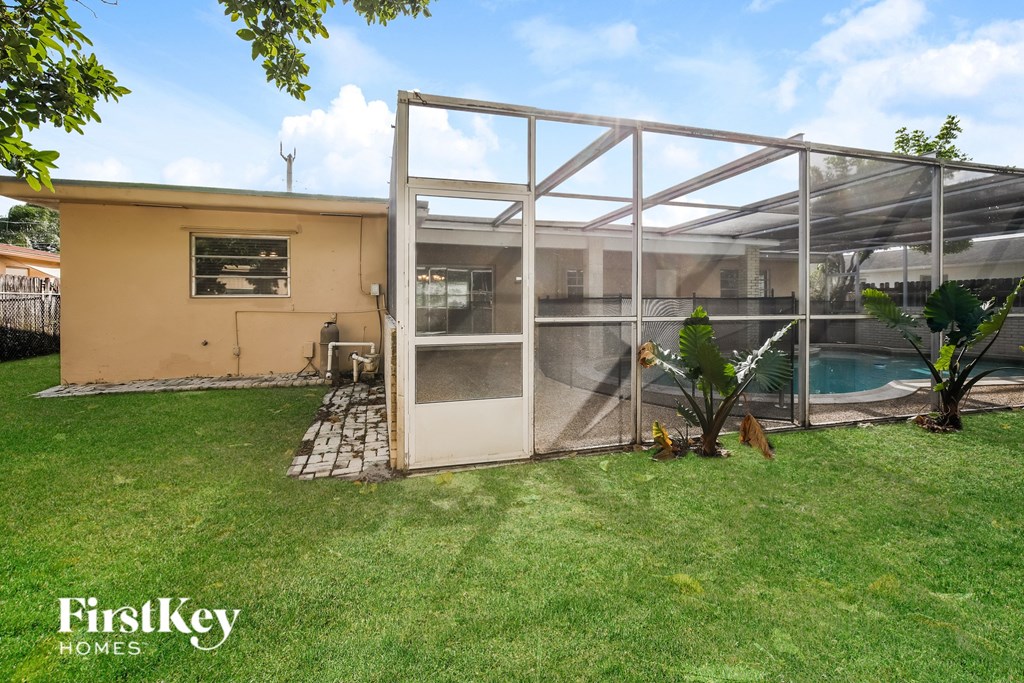 the backyard of a house with a pool and a greenhouse