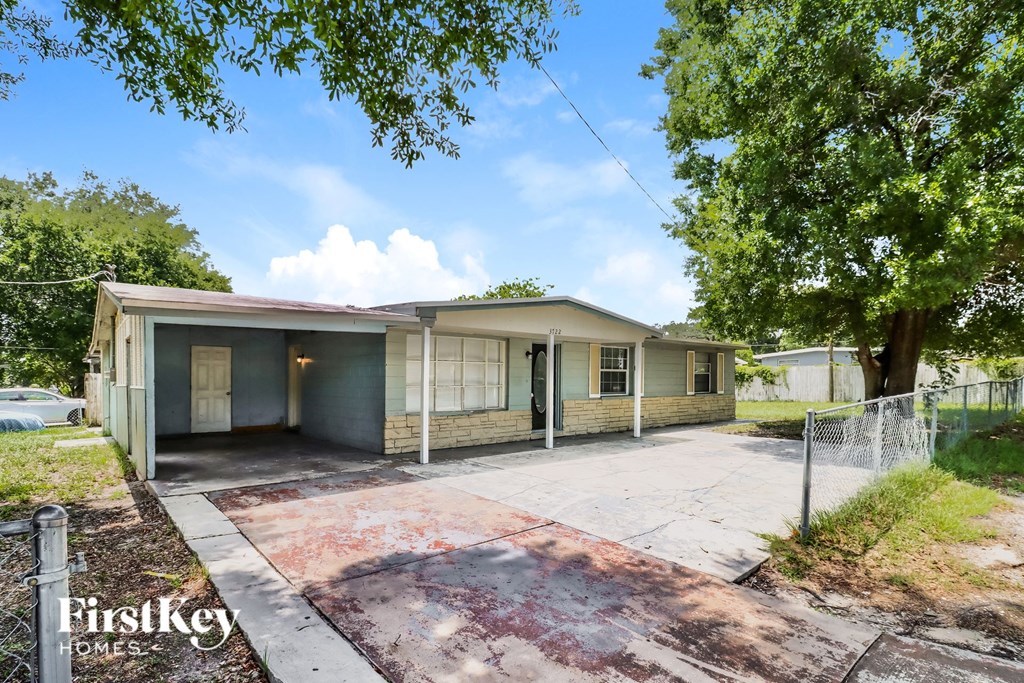 a small house with a driveway and a tree