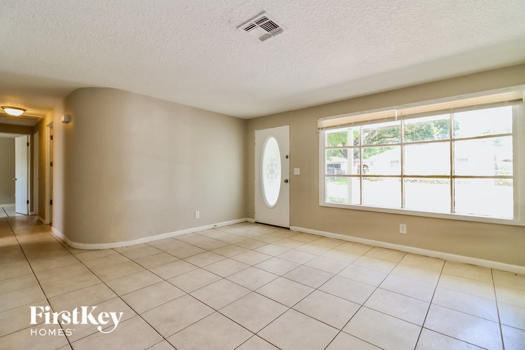 an empty living room with a large window and tiled floors