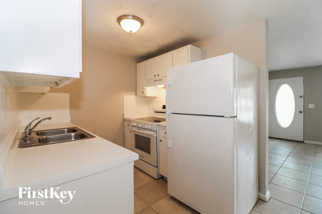 a kitchen with white cabinets and a refrigerator and a sink