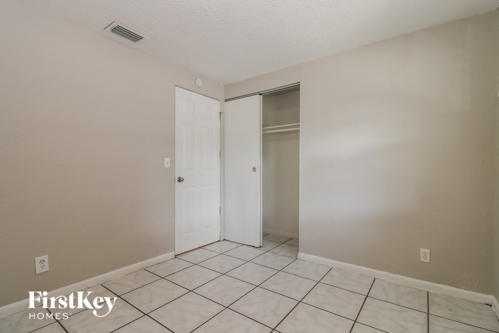 the living room of an apartment with a tiled floor and a closet