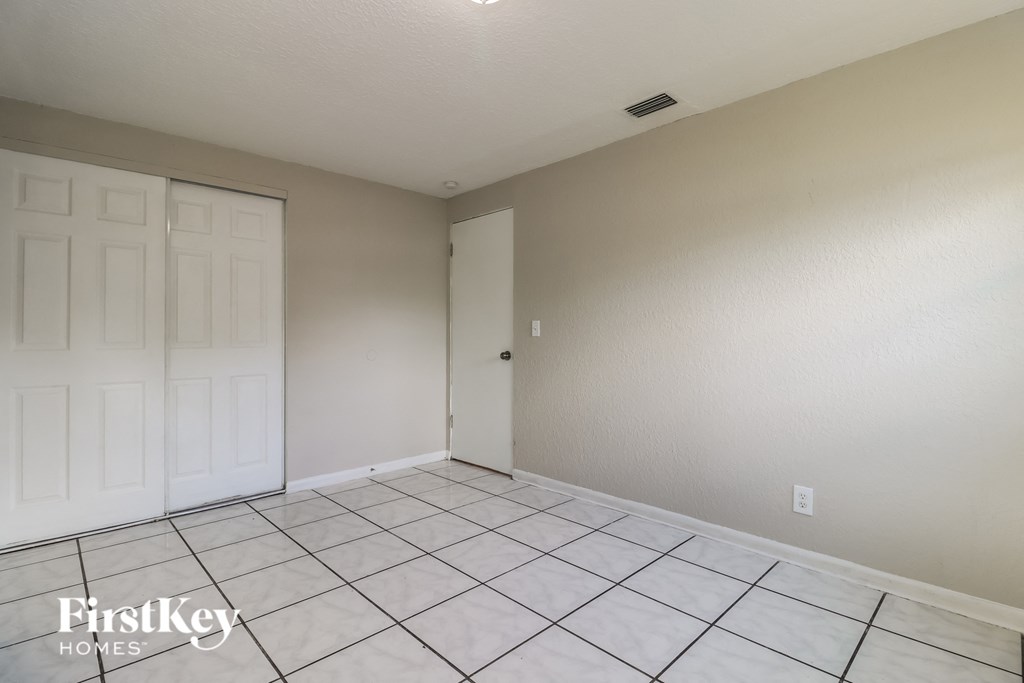 the living room of a home with a tiled floor and a closet