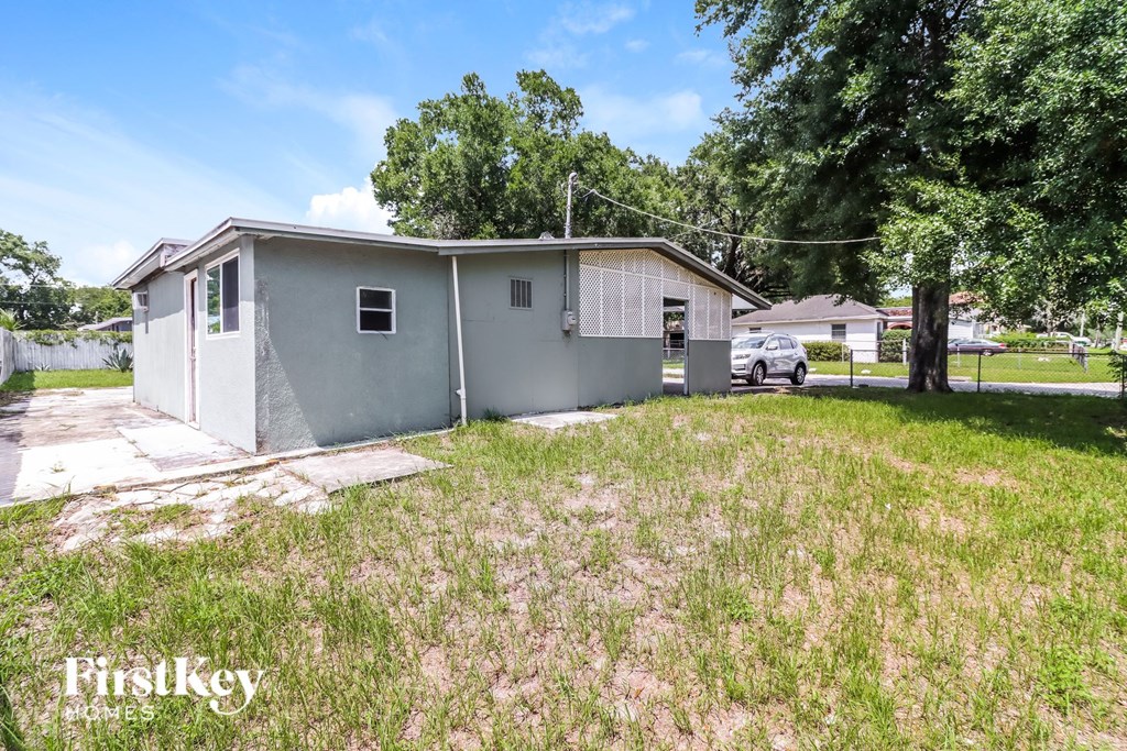 a small gray house with a yard and a car in the driveway