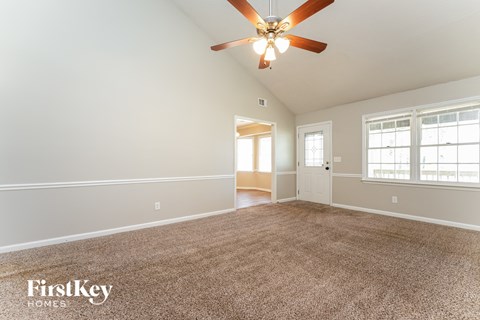 A spacious room with a ceiling fan and carpeted floor.