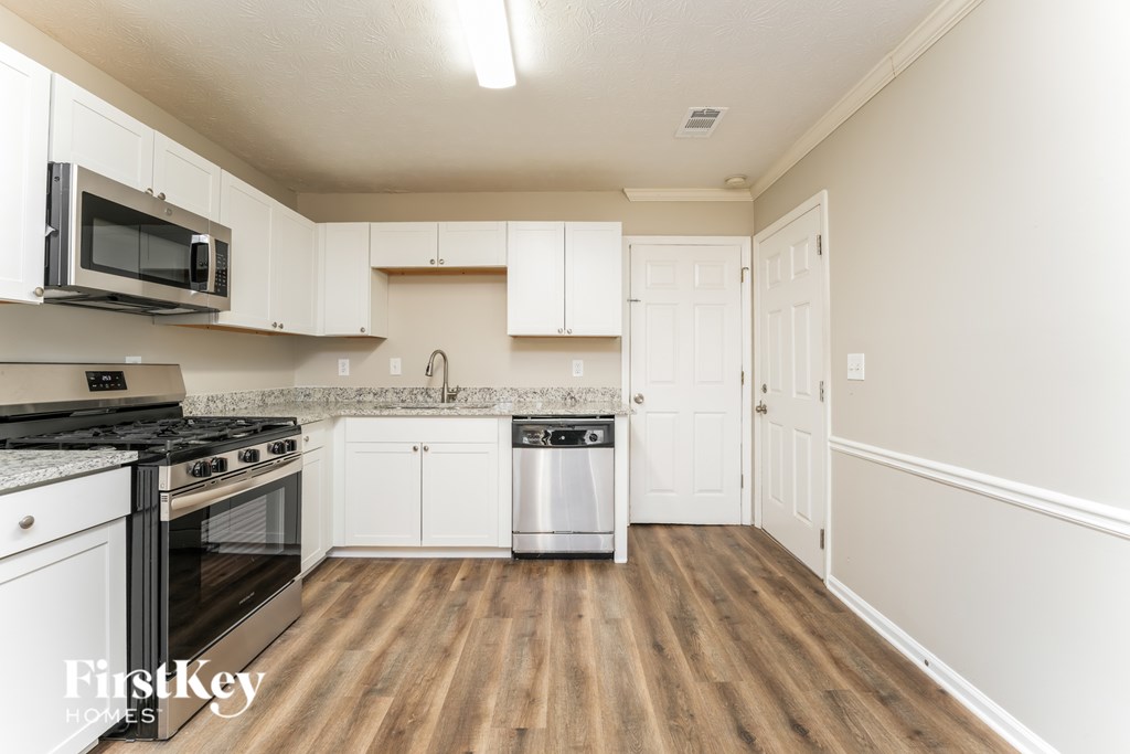 A kitchen with white cabinets and a wooden floor.