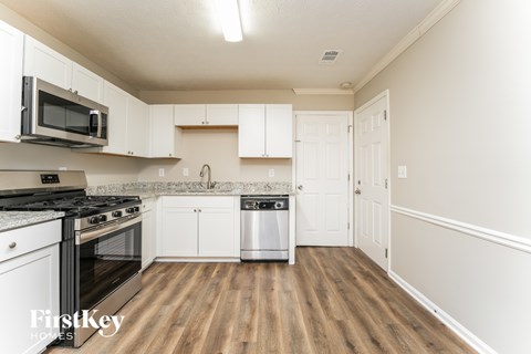 A kitchen with white cabinets and a wooden floor.