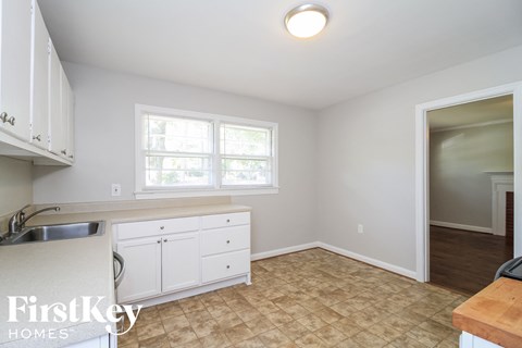 A kitchen with white cabinets and a beige floor.