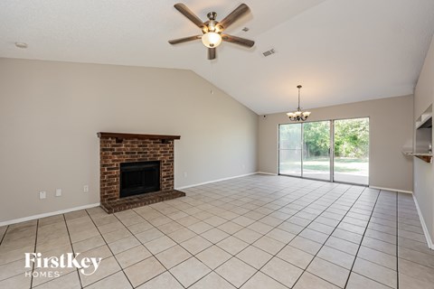 A spacious living room with a fireplace and a ceiling fan.
