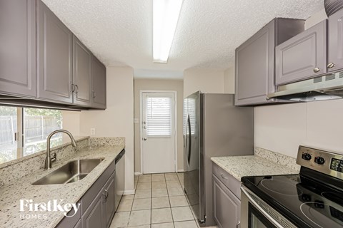 A kitchen with a stove top oven and a refrigerator.