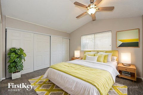 A bedroom with a bed, a ceiling fan, and a plant.