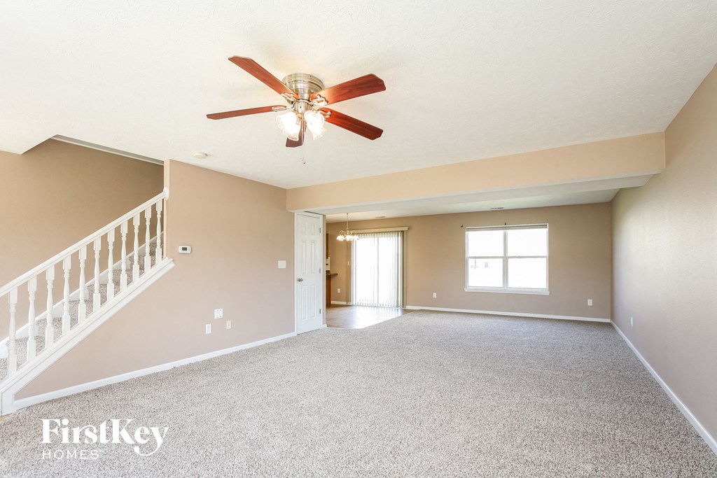an empty living room with a ceiling fan