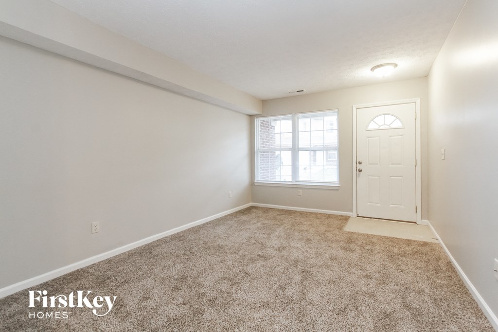 A room with a carpeted floor and a white door.