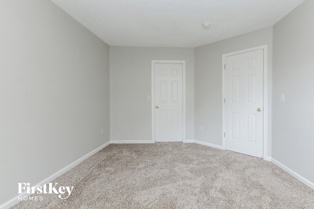A carpeted room with two doors and a FirstKey HOMES logo.