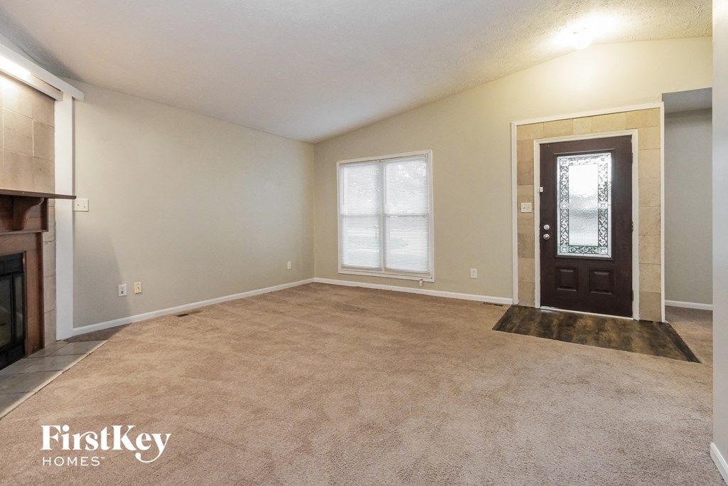 the living room of an empty house with a fireplace and a door