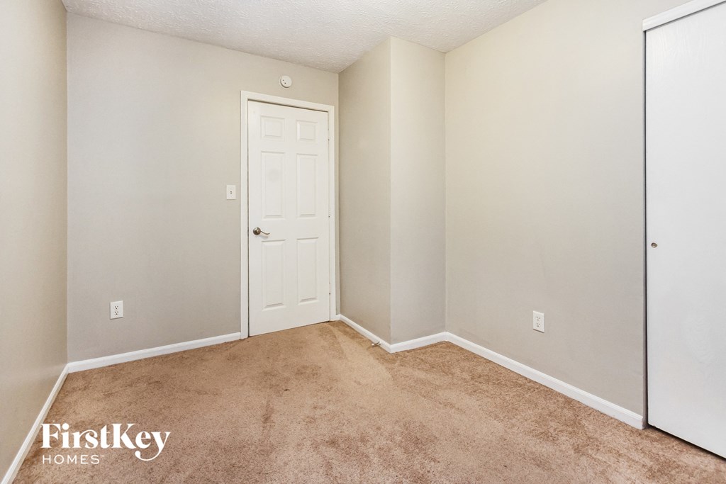 a bedroom with carpet and a door to a closet