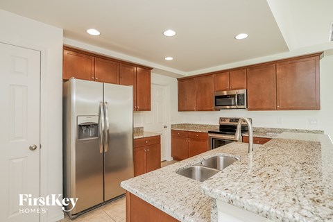 A kitchen with a granite counter top and a stainless steel refrigerator.