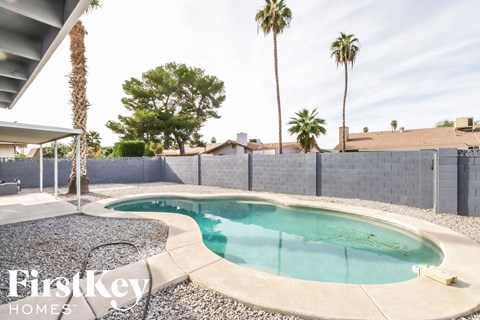 A pool surrounded by a concrete wall and a fence.