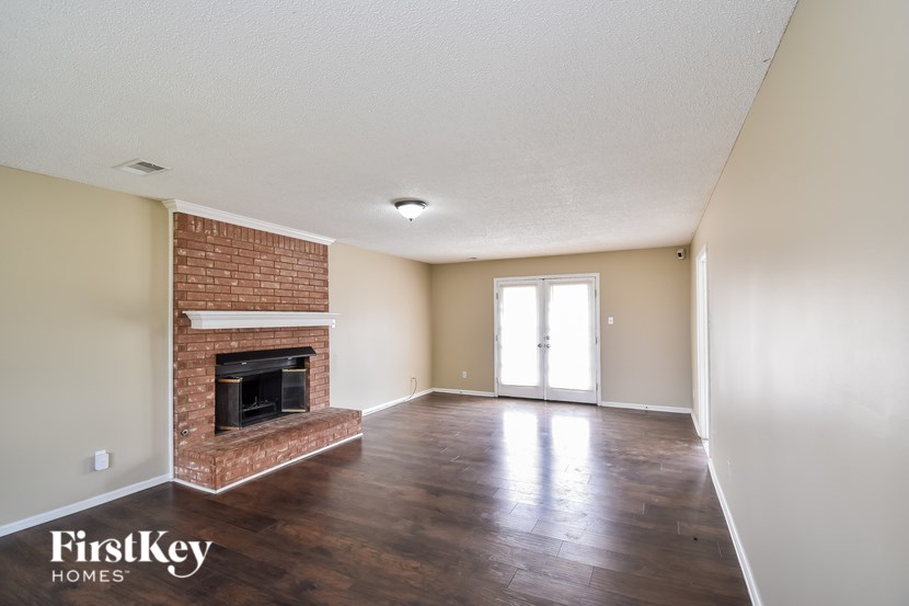 A room with a brick fireplace and wooden floors.