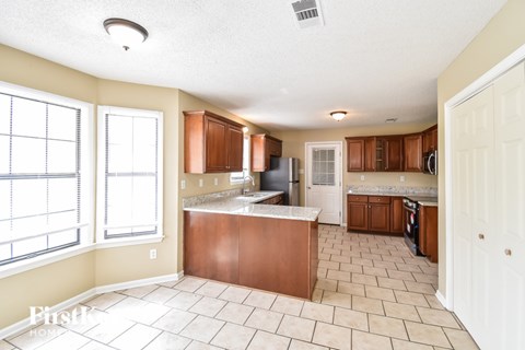 A kitchen with a brown counter top and white cabinets.