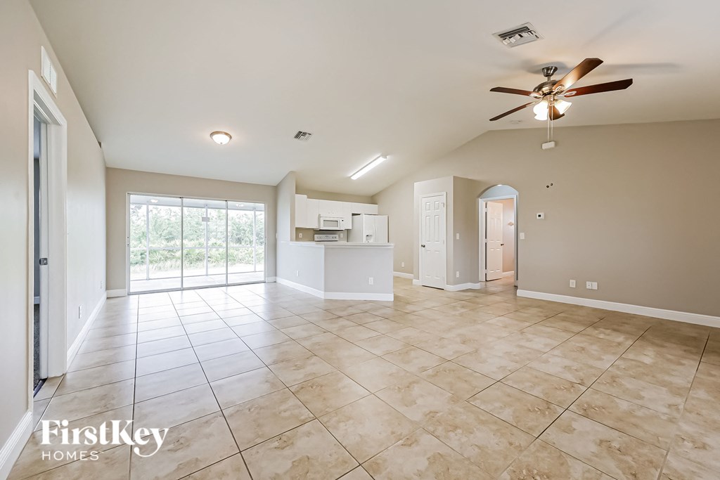 a spacious living room with tile flooring and a ceiling fan