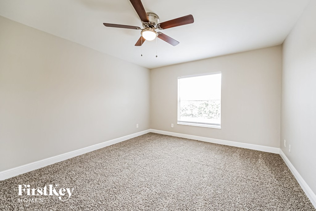 an empty room with a ceiling fan and a window