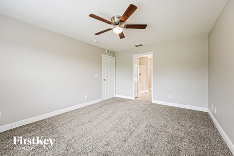 a spacious living room with carpet and a ceiling fan